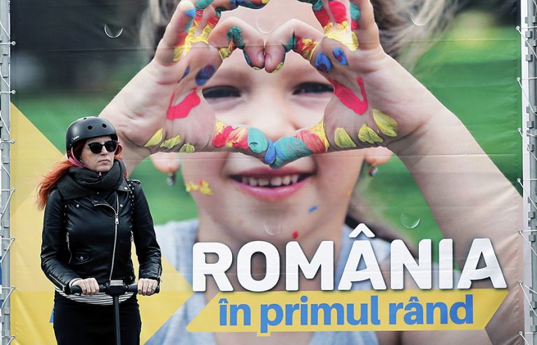 epa07450561 An young Romanian woman rides her electric scooter in front of a banner campaigning for European parliamentary elections on behalf of PNL (National Liberal Party), in Bucharest, Romania, 20 March 2019. The banner reads: 'Romania first'. European Union parliamentary elections will take place from 23 until 26 May 2019. EPA/ROBERT GHEMENT