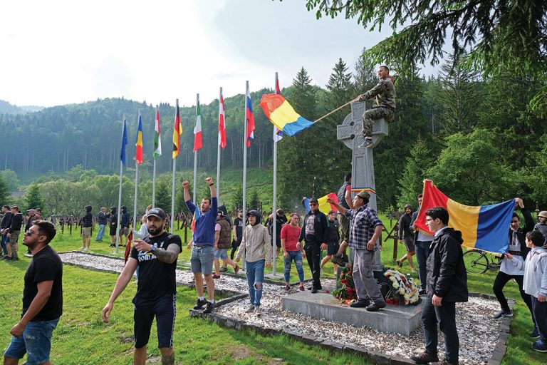 epa07632204 Romanian people wave Romanian flags at the International Heroes Cemetery in Valea Uzului (or Uzvolgye in Hungarian language), Harghita County, Romania, 06 June 2019 (issued 07 June 2019). Thousands of Romanian protesters broke through the police line to attend an orthodox dedication ceremony of a Romanian monument erected by the municipality of eastern Romanian town Darmanesti at the WWI memorial site. At the end of April 2019, Romanian tombstones were placed behind the Hungarian wooden crosses, which caused tensions between two nations. EPA/NANDOR VERES HUNGARY OUT