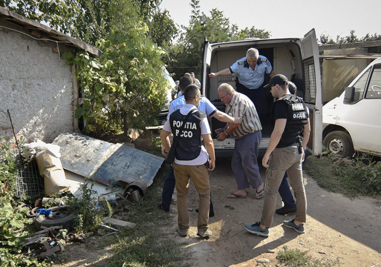 Police officers escort Gheorghe Dinca, the suspect in the case of rape and murder of a 15 year-old girl, to his home in Caracal, southern Romania, for further investigations, Saturday, July 27, 2019. Thousands of people took part Saturday evening in Bucharest in a march protesting the handling of the case, blaming Romanian officials for negligence, incompetence and a lack of empathy. (AP Photo/Bogdan Danescu)